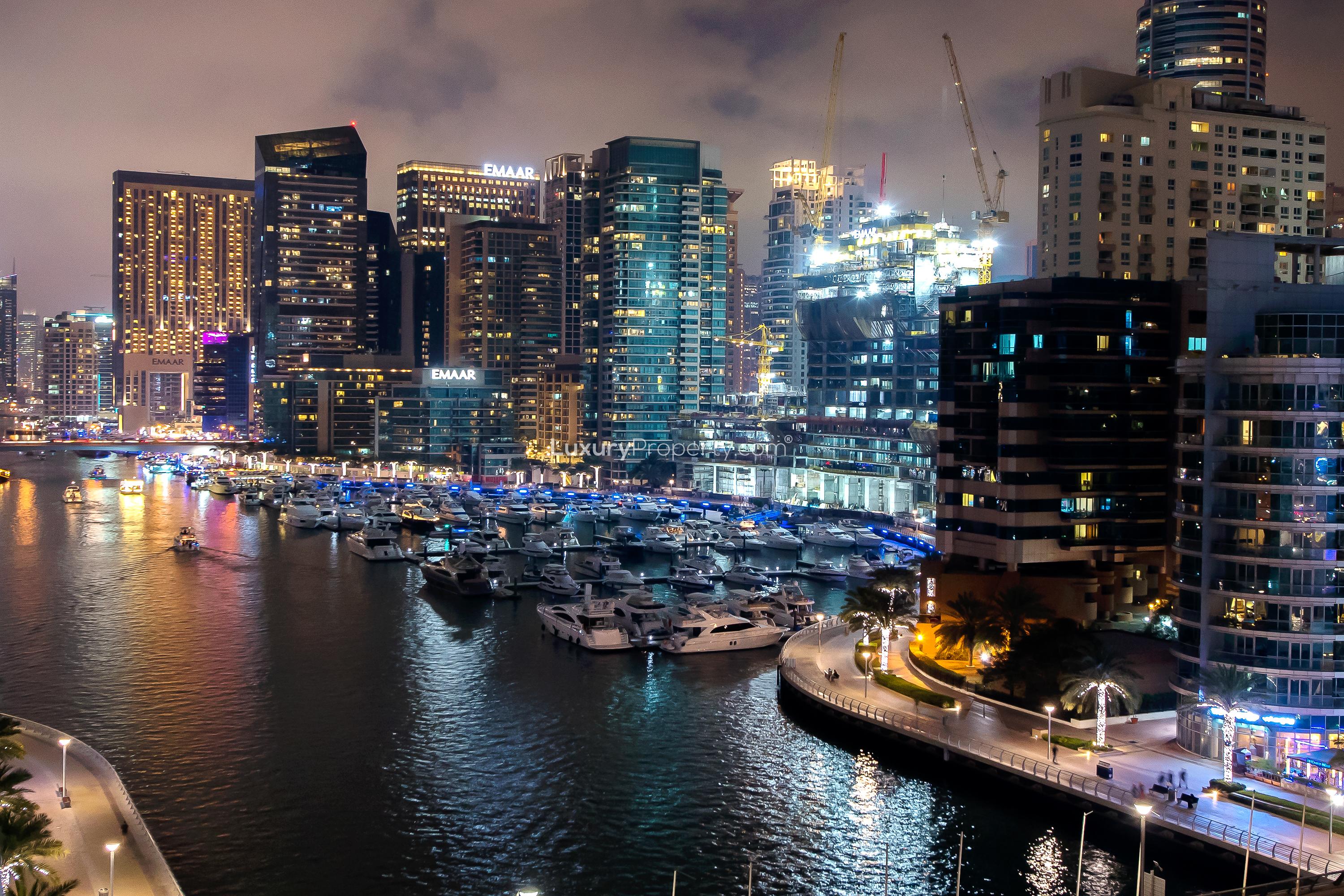 "Luxury pool area at Burj Al Nujoom apartment, Downtown Dubai, night view.",Night view of Downtown Dubai skyline, showcasing vibrant lights and marina yachts